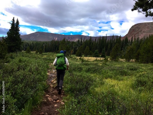 Man wearing backpack hiking in mountain field