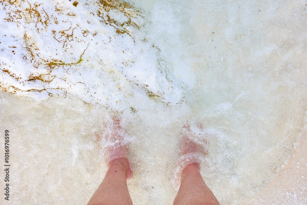 Fototapeta premium A person's feet are in the water, and the water is white
