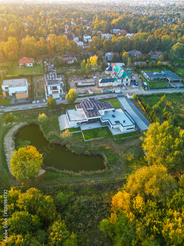 Aerial autumn perspective of a new sustainable luxury villa built in the countryside with solar panels on the roof., sunset light.