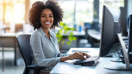 Smiling businesswoman sitting in front of a computer in a modern office, surrounded by greenery, creating a pleasant and productive work atmosphere.