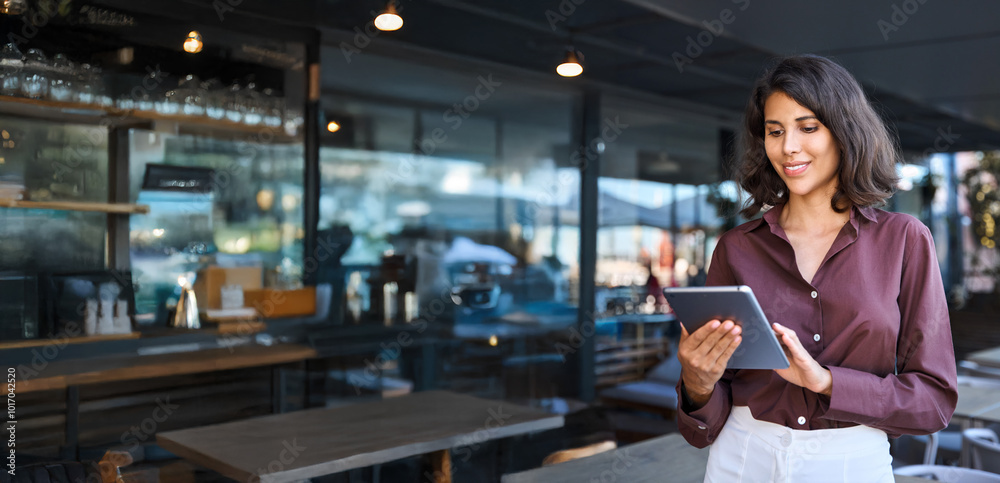 Young adult female entrepreneur owner of coffee shop or bar restaurant using tablet pc application for work. Indian or latin hispanic woman holding digital computer for business. Banner, copy space Young adult female entrepreneur owner of coffee shop or bar restaurant using tablet pc application for work. Indian or latin hispanic woman holding digital computer for business. Banner, copy space