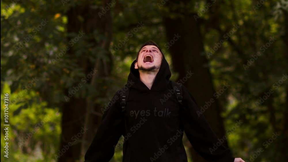 A man stands in the forest, yelling angrily, expressing intense emotions amidst the tall trees and dense foliage. A man stands in the forest, yelling angrily, expressing intense emotions amidst the tall trees and dense foliage.