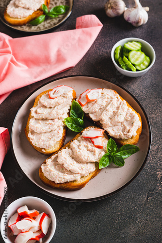 Delicious sandwiches with crab meat and cucumber pate on a plate on the table vertical view