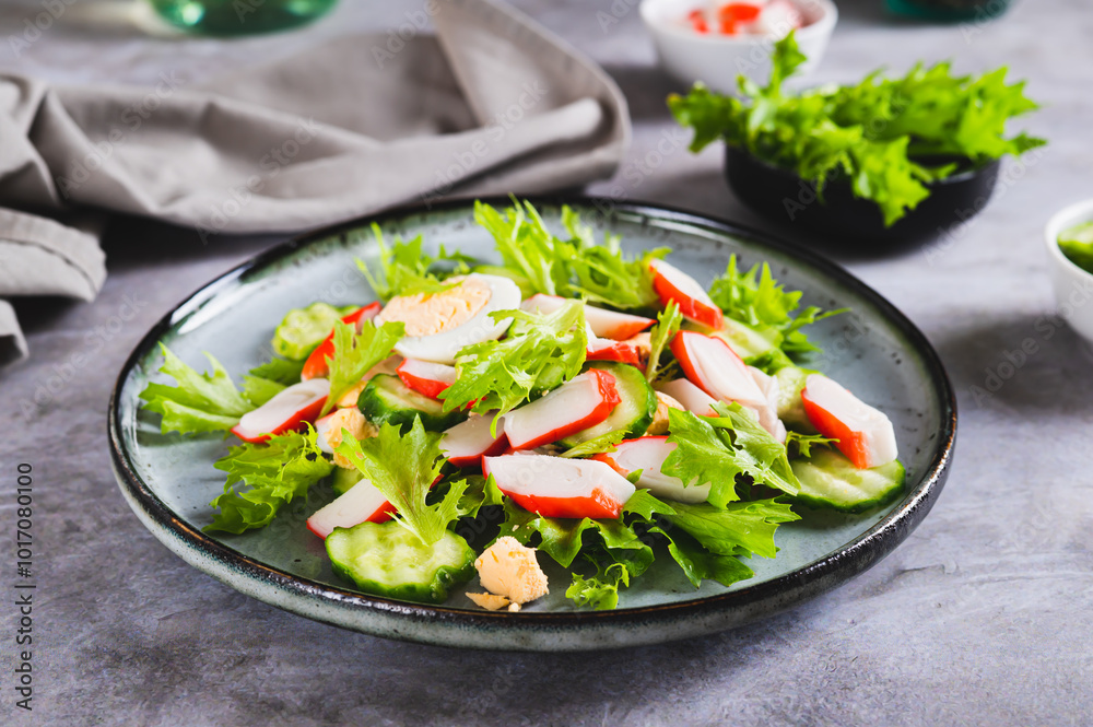Light salad of crab sticks, cucumber, boiled egg and lettuce on a plate on the table Light salad of crab sticks, cucumber, boiled egg and lettuce on a plate on the table