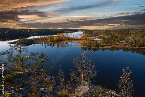 Autumn landscape. View of Lake Ladoga from the top of Linnasaari island. Calm water with reflected trees and sky. Beautiful sunset.