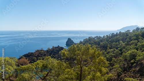 Turkish Mediterranean coastline as seen from the Lycian Way in Antalya, Turkey with a blue sea, lush green forests, and rugged rocky shores, attracting tourists every summer. photo