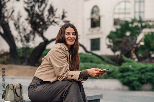 Happy businesswoman holding smartphone smiling outdoors