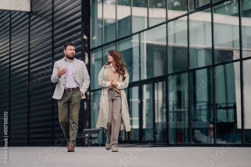 Business people walking and talking in front of modern office building photo