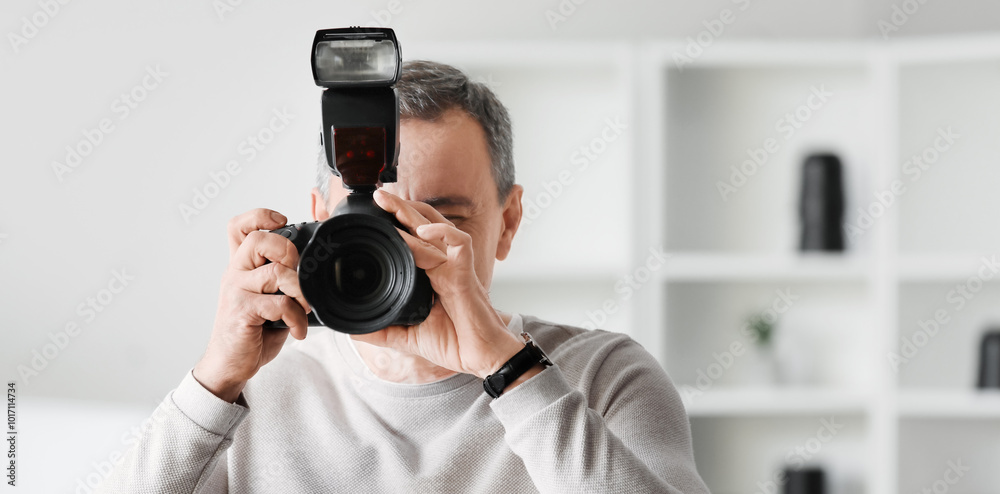 Mature photographer with professional camera in studio, closeup