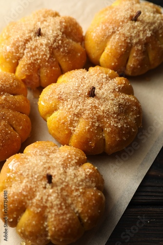 Parchment with tasty pumpkin shaped buns on wooden table, closeup