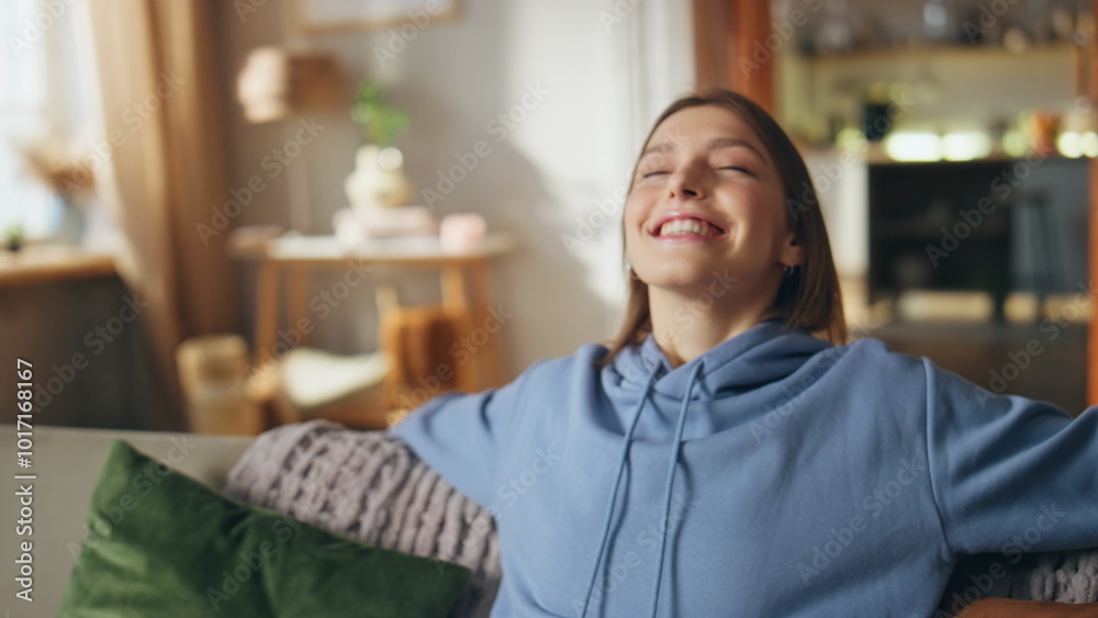 Dreamy girl sitting sofa with cheerful smile closeup. Happy woman relaxing couch