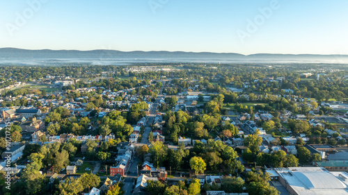 Obraz na płótnie Aerial view of Carlisle, PA, showcasing a mix of residential, commercial buildings, and tree-lined streets under a clear morning sky