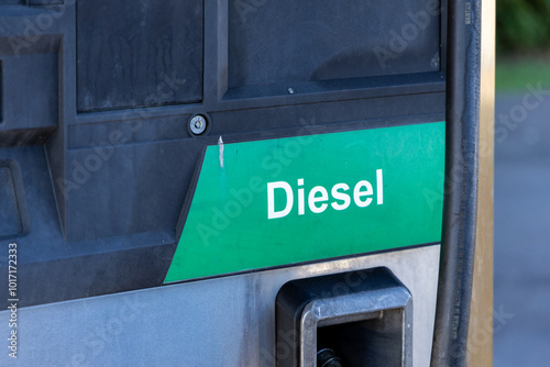 Close-up of a diesel fuel pump with a yellow nozzle, highlighting fuel-related concerns such as rising prices, shortages, and the shift toward electric vehicles amid climate change challenges.