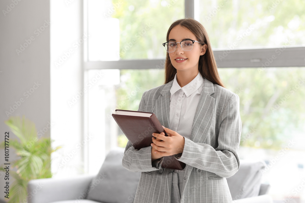 Beautiful young happy businesswoman with notebook near window in office Beautiful young happy businesswoman with notebook near window in office