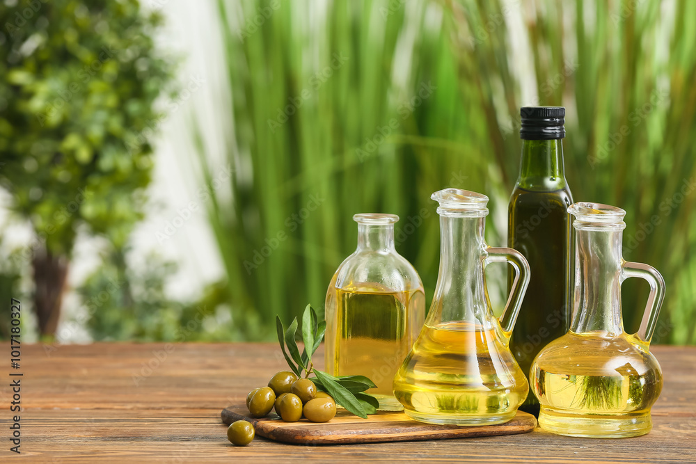 Jugs of oil with olives on wooden table against blurred background Jugs of oil with olives on wooden table against blurred background