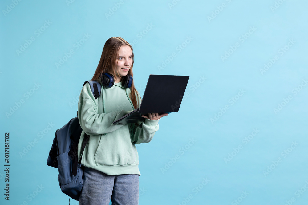 Obraz premium Upbeat teenager opening laptop, excited to start job shift, isolated over studio background. Portrait of radiant girl with notebook ready to do business related tasks on it