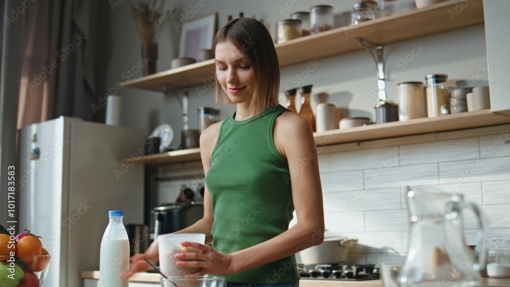 Domestic lady pouring flakes to glass bowl at comfortable kitchen closeup.