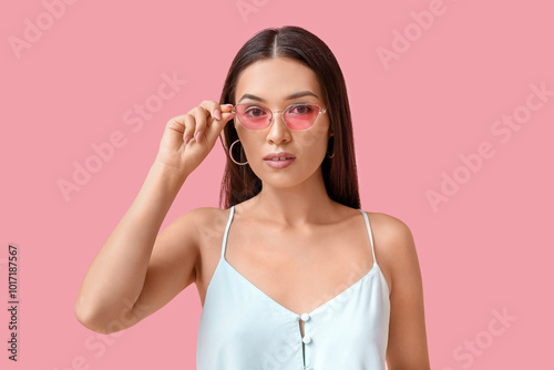 Beautiful young Asian woman with stylish mint makeup in sunglasses on pink background