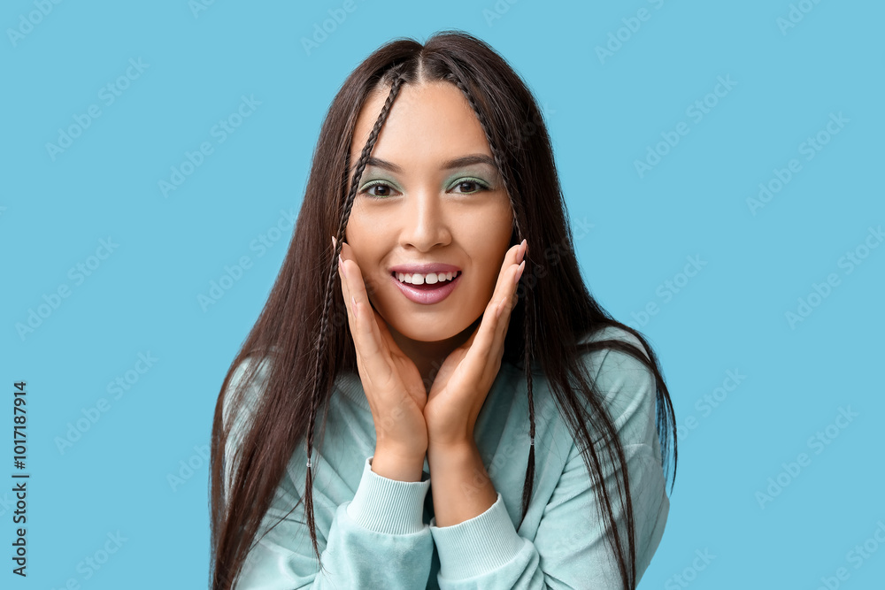 Smiling young Asian woman with stylish mint makeup on blue background Smiling young Asian woman with stylish mint makeup on blue background
