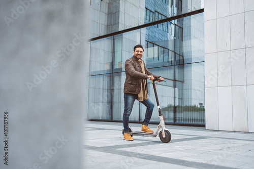 A man rides an electric scooter around the city in front of the glass building where he works