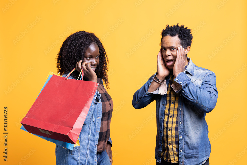 Anxious african american husband getting worried about spending money after his wife purchased many clothes, shopping bags. Young woman shopaholic buying things on discount. Anxious african american husband getting worried about spending money after his wife purchased many clothes, shopping bags. Young woman shopaholic buying things on discount.