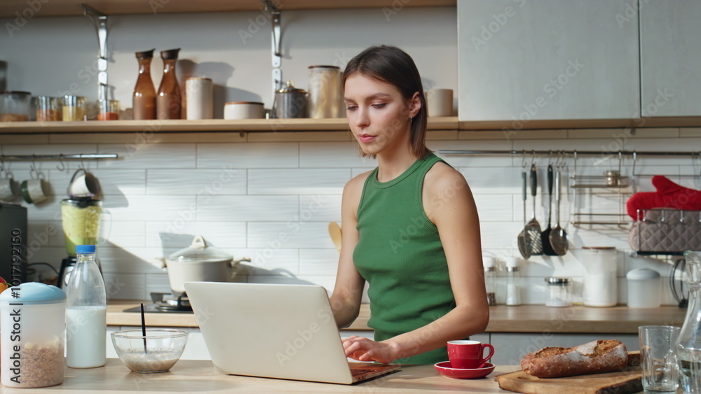 Drinking lady looking laptop on kitchen home closeup. Woman working computer Drinking lady looking laptop on kitchen home closeup. Woman working computer
