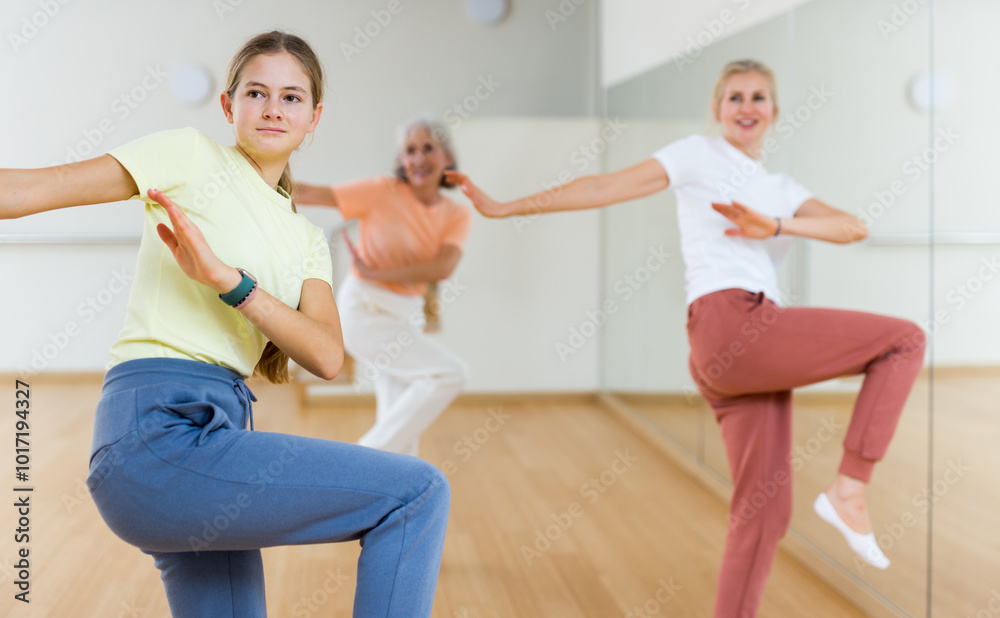 Obraz premium Teenage girl performing dance during group training in studio.