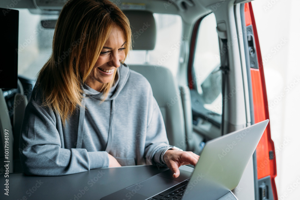 Blonde woman smiling while working in van Blonde woman smiling while working in van