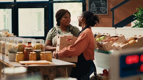 Employee receiving products from farmers daughter, dealing with supplying the local grocery store with freshly harvested produce. African american vendor acquiring more eco friendly merchandise.