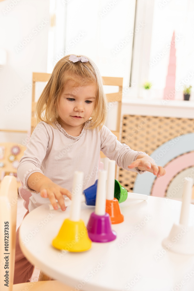 Happy toddler girl playing with bells in the kindergarten Happy toddler girl playing with bells in the kindergarten