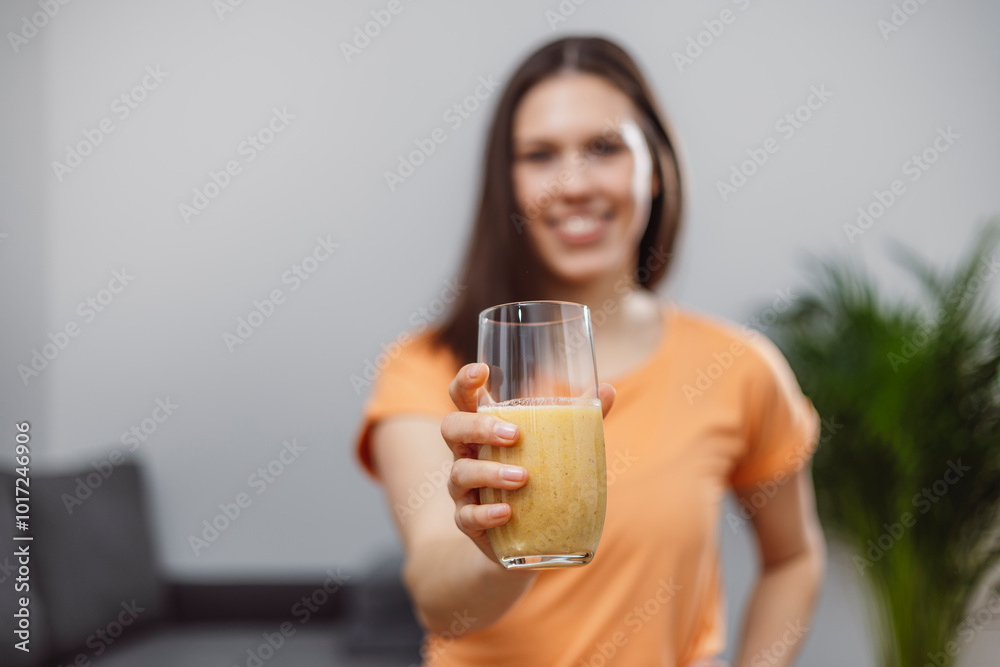 A young woman drinks a vegetable and fruit smoothie in her living room and doing yoga on yoga mat. A young woman drinks a vegetable and fruit smoothie in her living room and doing yoga on yoga mat.