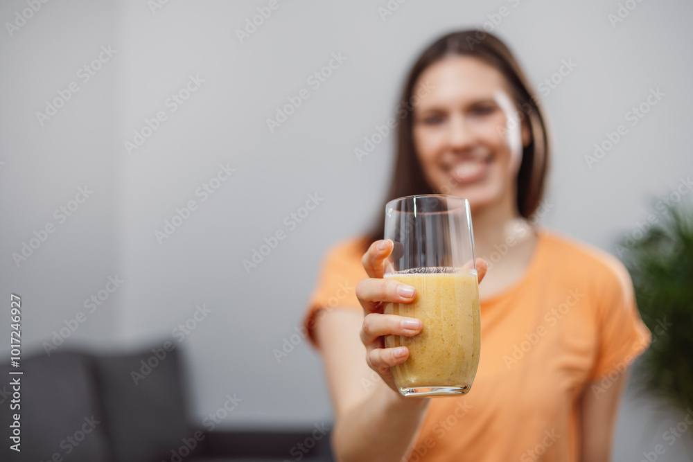 A young woman drinks a vegetable and fruit smoothie in her living room and doing yoga on yoga mat. A young woman drinks a vegetable and fruit smoothie in her living room and doing yoga on yoga mat.