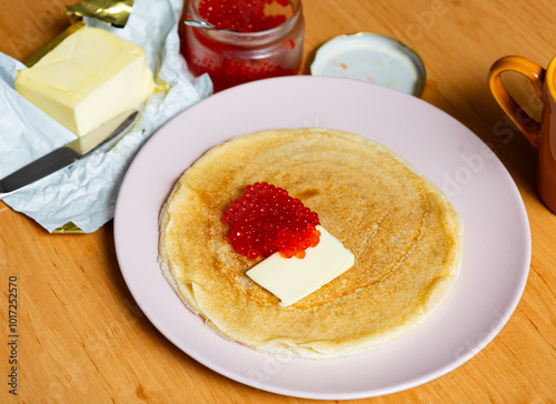 Photography Pancakes with piece of butter and red caviar dished up in flat service plate