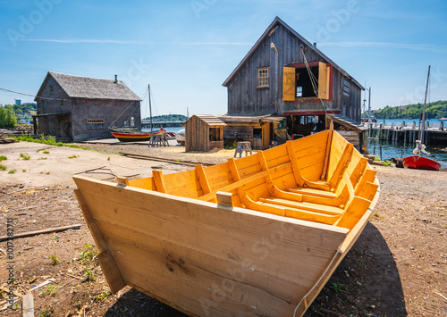 A wooden dory awaits paint and finishing touches outside a boat house photo