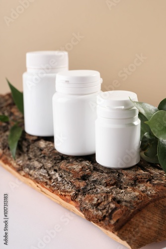 Plastic medical bottles, green leaves and snag on white table, closeup