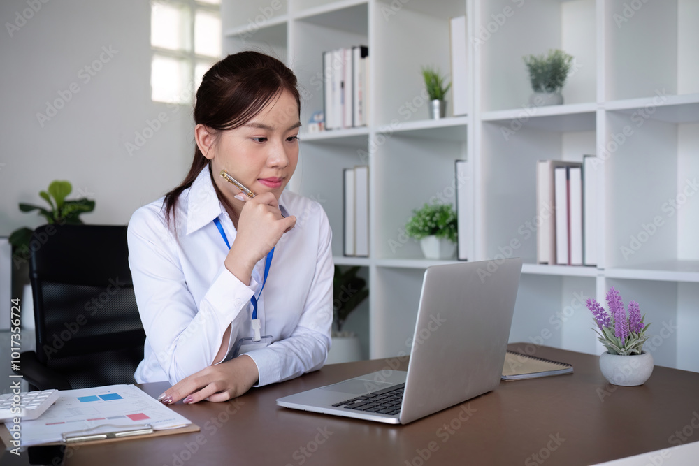 Focused Business Woman Working on Documents at Office Desk with Laptop and Notepad Focused Business Woman Working on Documents at Office Desk with Laptop and Notepad