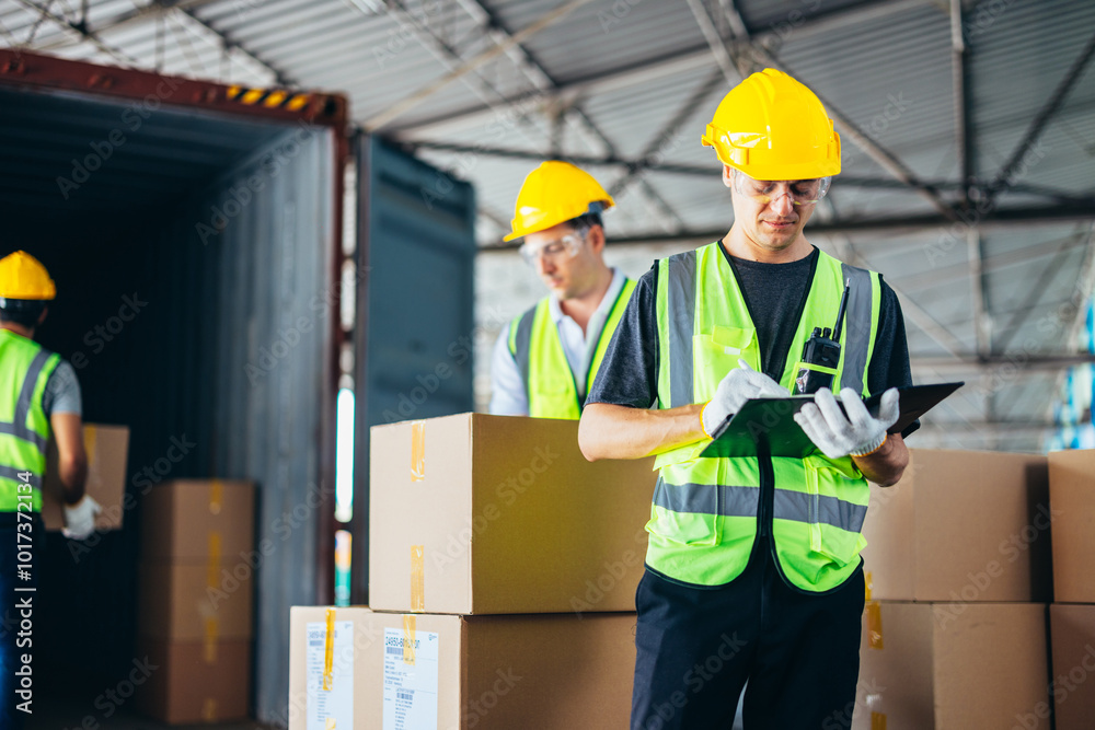 Three warehouse workers using a digital tablet while recording inventory. Logistics employees working with warehouse management software in a large distribution centre. Three warehouse workers using a digital tablet while recording inventory. Logistics employees working with warehouse management software in a large distribution centre.