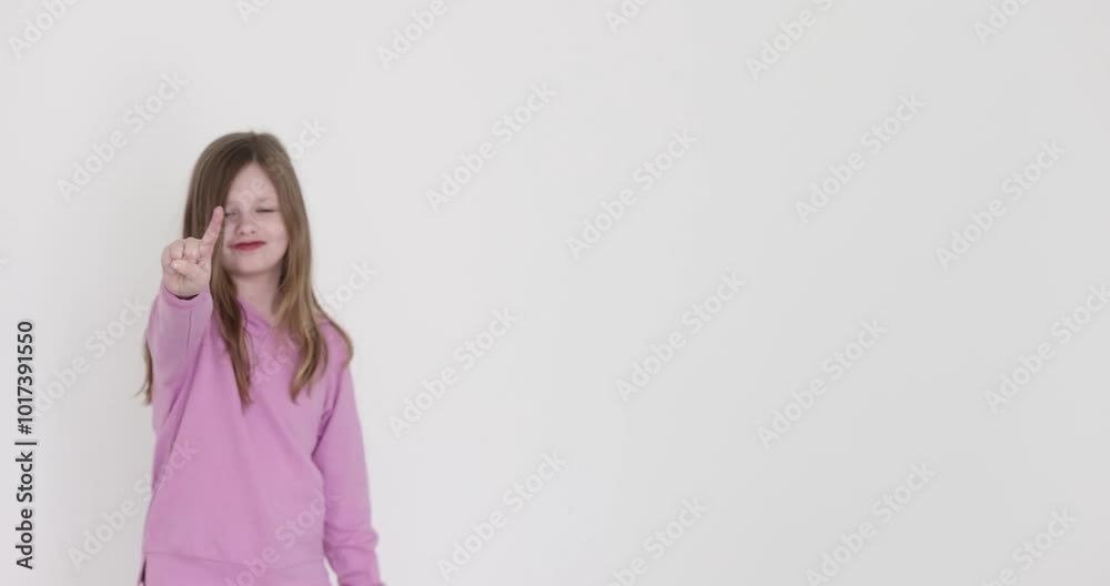 Smiling little girl points with index finger on white background. Curious child with happy facial expression pays attention with gesture Smiling little girl points with index finger on white background. Curious child with happy facial expression pays attention with gesture