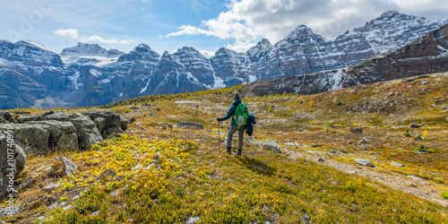 Incredible fall time views at Larch Valley and scenic Sentinal Pass during September with bright yellow trees and landscape covering the wild, wilderness area Banff National Park with hiker woman