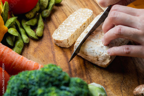 Fotografie slice raw tempeh block with other vegetables ingredients on a wooden board