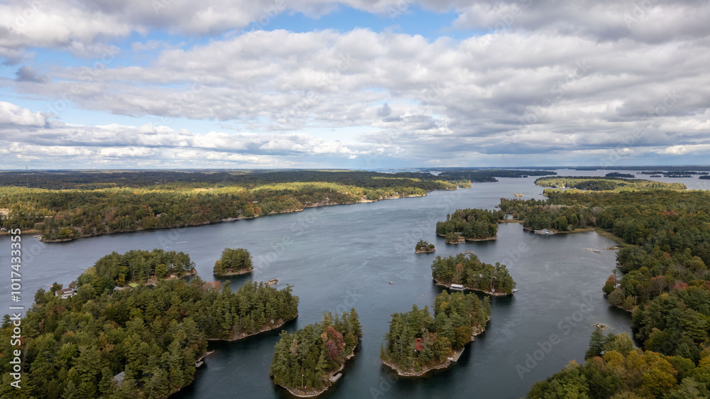 Fototapeta premium Stunning aerial views of the 1000 Islands region along the United States and Canada border, showcasing a mesmerizing landscape of lush green islands scattered across the blue waters of the St. Lawrenc