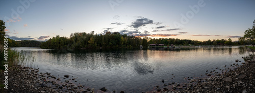 Green Lakes State Park in Syracuse offers a peaceful view of its crystal-clear waters, framed by lush trees. The sunset glow casts a soft light on the serene lake, making it a perfect spot for reflect