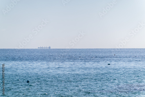 Calm blue sea with the silhouette of a large ship on the horizon