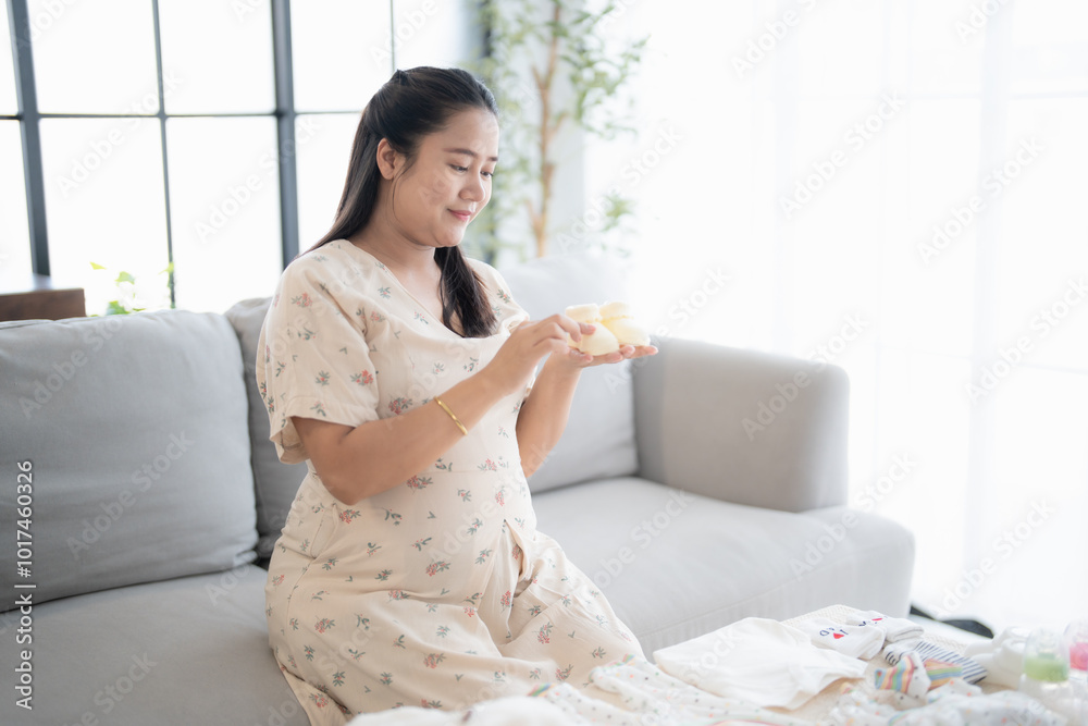 Pregnant asian woman getting ready for the maternity hospital preparing and planning baby clothes for new baby of pregnancy packing baby stuff on bed. Pregnant asian woman getting ready for the maternity hospital preparing and planning baby clothes for new baby of pregnancy packing baby stuff on bed.