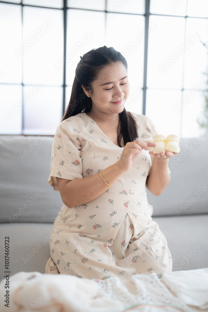 Pregnant asian woman getting ready for the maternity hospital preparing and planning baby clothes for new baby of pregnancy packing baby stuff on bed. Pregnant asian woman getting ready for the maternity hospital preparing and planning baby clothes for new baby of pregnancy packing baby stuff on bed.