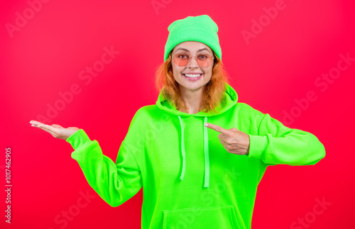 Minimal outfit. Redhead woman wearing hoodie casual clothes isolated on pink. Lifestyle concept. Woman model wearing hoodie. Attractive woman has stylish look. Girl look cool. Point finger