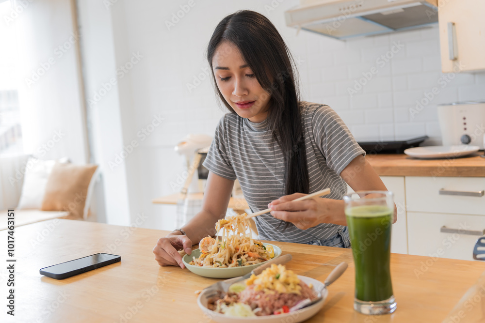 Asian Girl eating Thai food in kitchen counter Home delivery food feeling happy Asian Girl eating Thai food in kitchen counter Home delivery food feeling happy