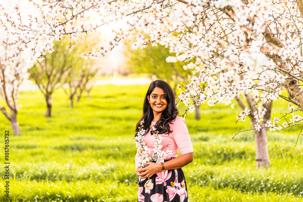 Smiling woman holding almond blossoms in a blooming orchard Smiling woman holding almond blossoms in a blooming orchard