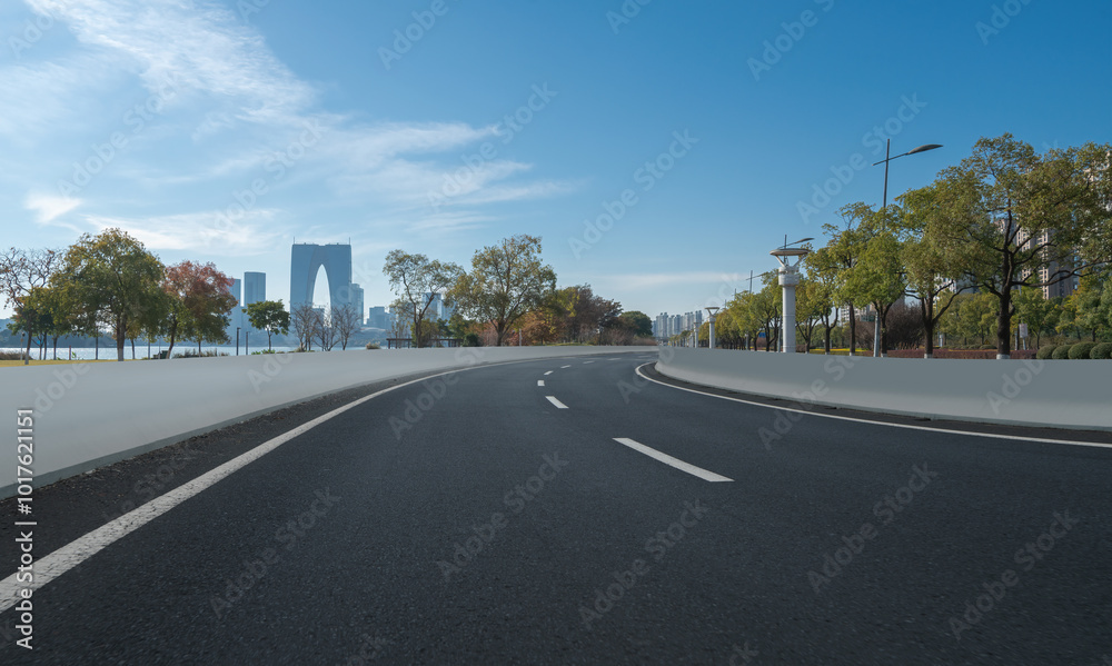 Fototapeta premium Serene City Road with Scenic Urban Skyline and Lush Trees