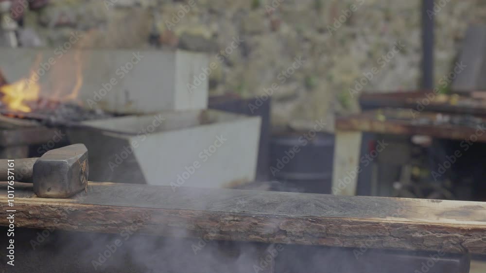 Close-up of a blacksmith's hands working with burning metal on an anvil and wooden board. Close-up of a blacksmith's hands working with burning metal on an anvil and wooden board.